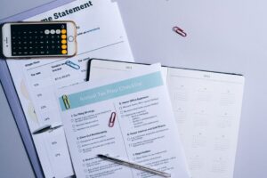 A person reviews a property tax bill and calculator at a kitchen table with documents spread out.