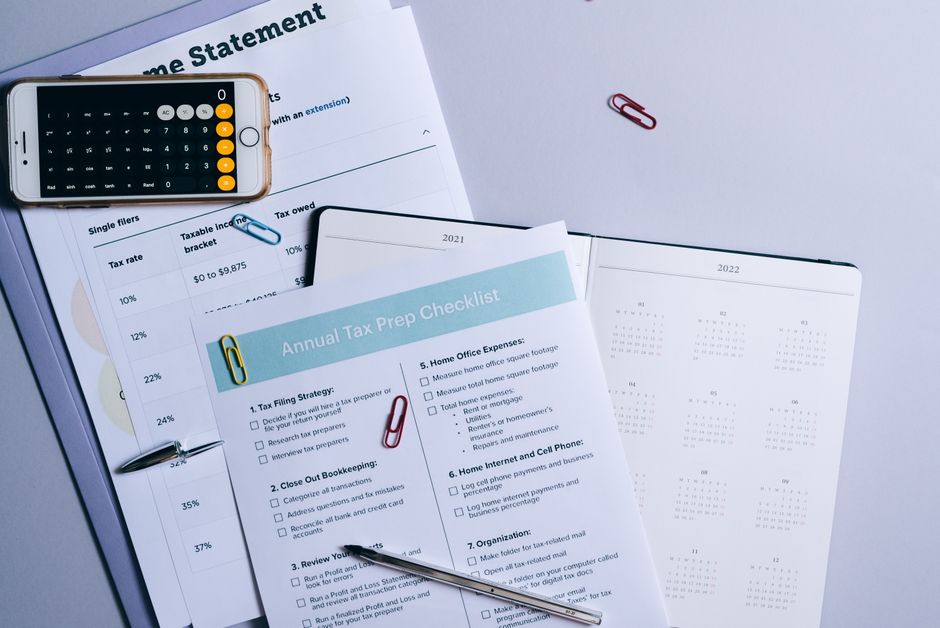 A person reviews a property tax bill and calculator at a kitchen table with documents spread out.